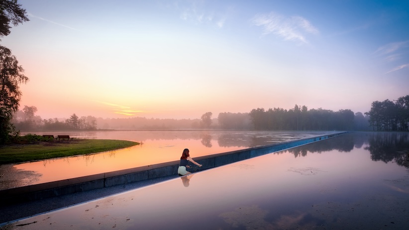 Fietser fietst tussen het water bij zonsondergang